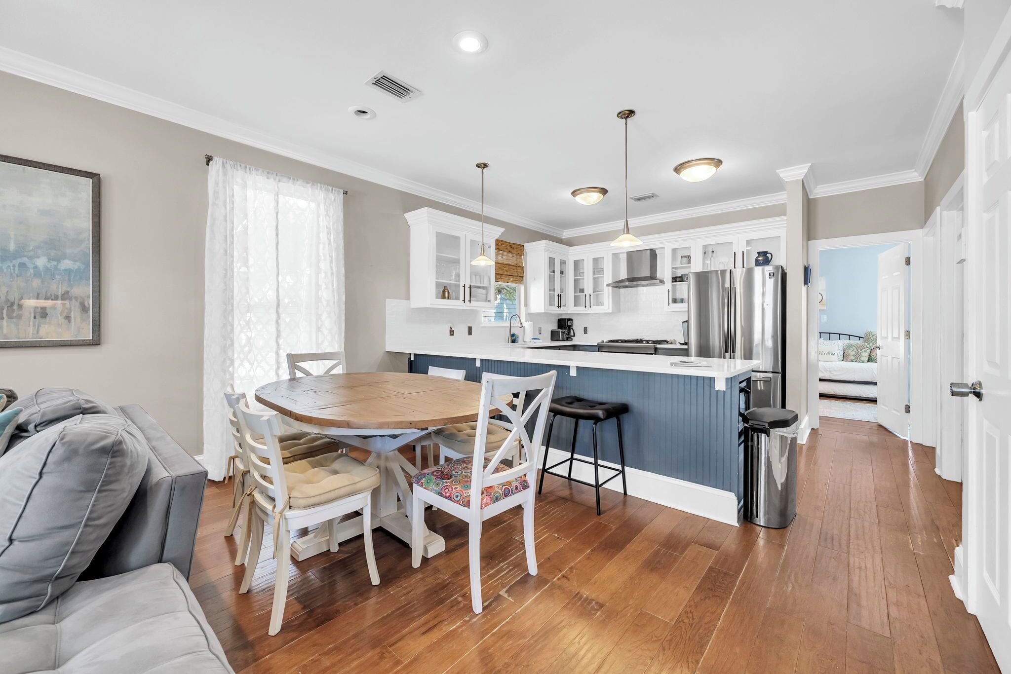 A modern kitchen with white cabinets, stainless steel appliances, and a wooden dining table.