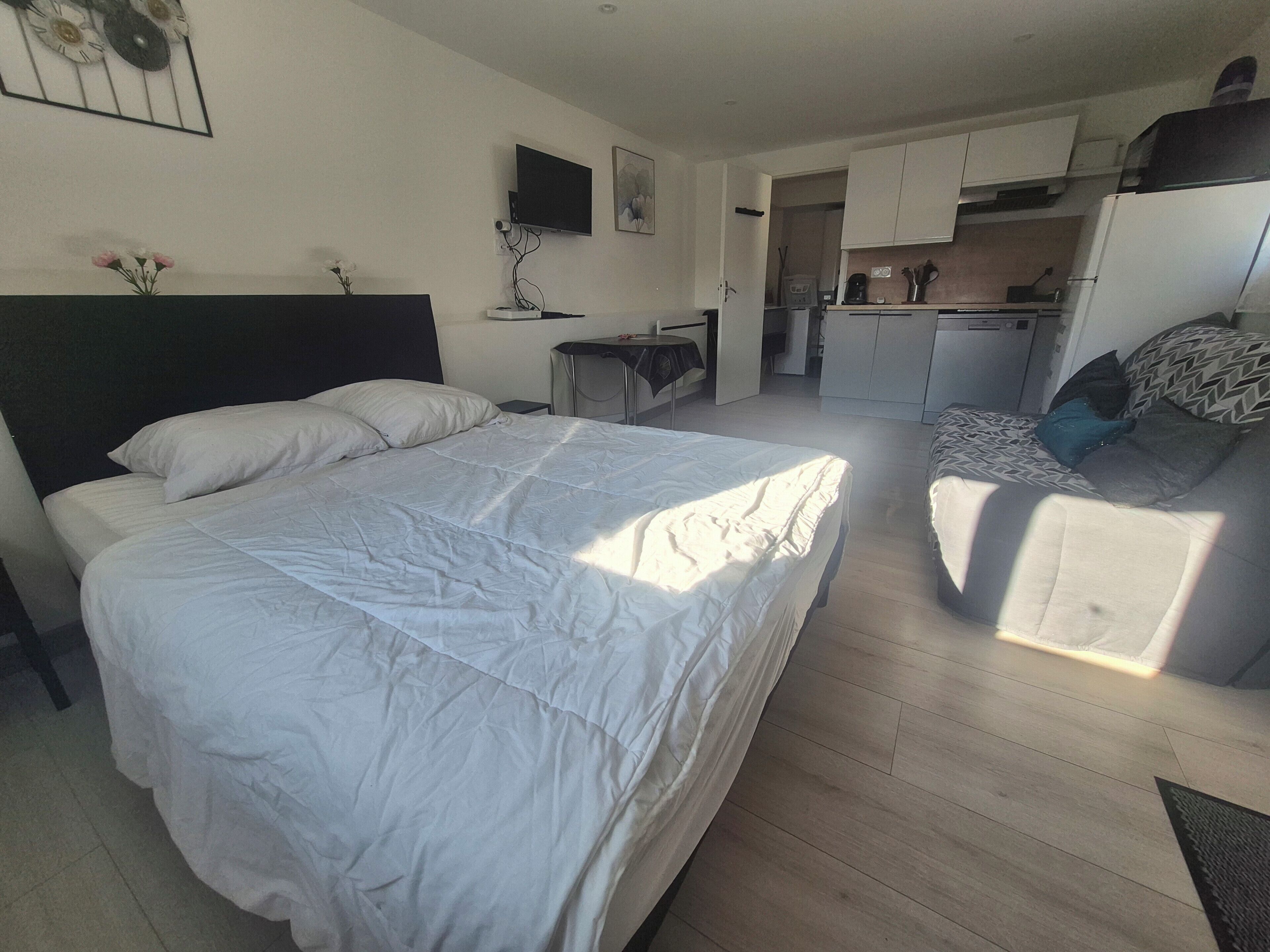 Ein Schlafzimmer mit einem großen Bett, einem Schreibtisch und einer kleinen Küche im Hintergrund.