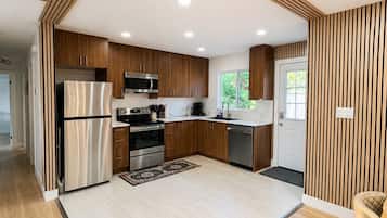 A modern kitchen with wooden cabinetry, stainless steel appliances, and a central island.