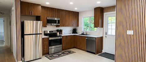 A modern kitchen with wooden cabinetry, stainless steel appliances, and a central island.