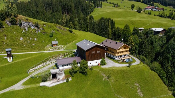 An aerial view of a rural property with a large wooden barn, a guesthouse, and surrounding green fields. - Holiday With Mountain Views in Mittersill (Mittersill)