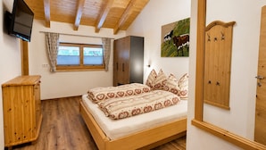 A bedroom with a wooden bed, a wardrobe, a television, and a window with curtains. - Holiday With Mountain Views in Mittersill (Mittersill)