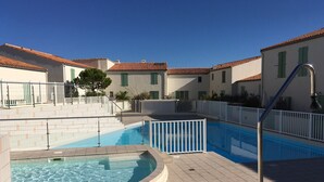 A swimming pool area with a hot tub, surrounded by buildings with red-tiled roofs and white walls. - Elegant apartment close to the port and the market (Saint-Martin-de-Ré)