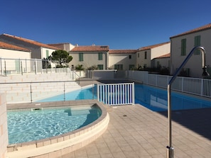 A swimming pool area with a hot tub, surrounded by buildings with red-tiled roofs and white walls. - Elegant apartment close to the port and the market (Saint-Martin-de-Ré)