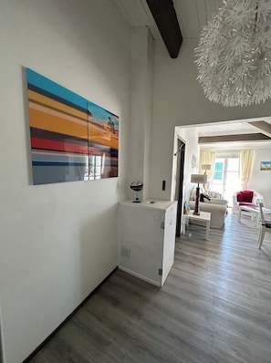 A spacious living area with a modern design, featuring a white cabinet, a dining table, and a sofa. - Elegant apartment close to the port and the market (Saint-Martin-de-Ré)