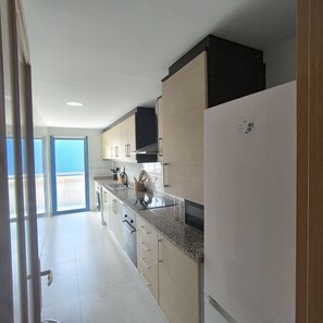 A modern kitchen with a built-in oven, a microwave, and a refrigerator. - Puntarró (Peñiscola)