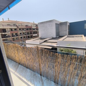 A rooftop terrace with a view of surrounding buildings, a bamboo fence, and a clear sky. - Puntarró (Peñiscola)
