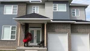 A modern two-story house with a front porch, a garage, and a well-maintained lawn.