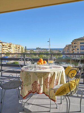 A table set outdoors with a view of buildings and the sea. - RicosRincones · Ocean View Apartment (San Pedro Alcántara)