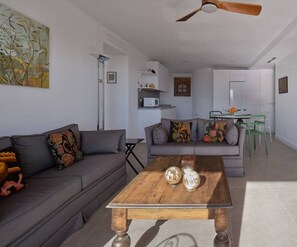 A modern living room with a grey sofa, a wooden coffee table, and a ceiling fan. - Ocean View Apartments on Boulevard, Apartame. (San Pedro Alcántara)