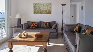 Een moderne woonkamer met een grijze bank, een houten salontafel en een vloerlamp.