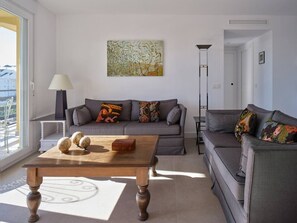 Ein modernes Wohnzimmer mit einem grauen Sofa, einem Holztisch und einer Stehlampe.