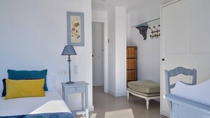 Een slaapkamer met twee bedden, een nachtkastje, een lamp, een stoel en een kledingkast.