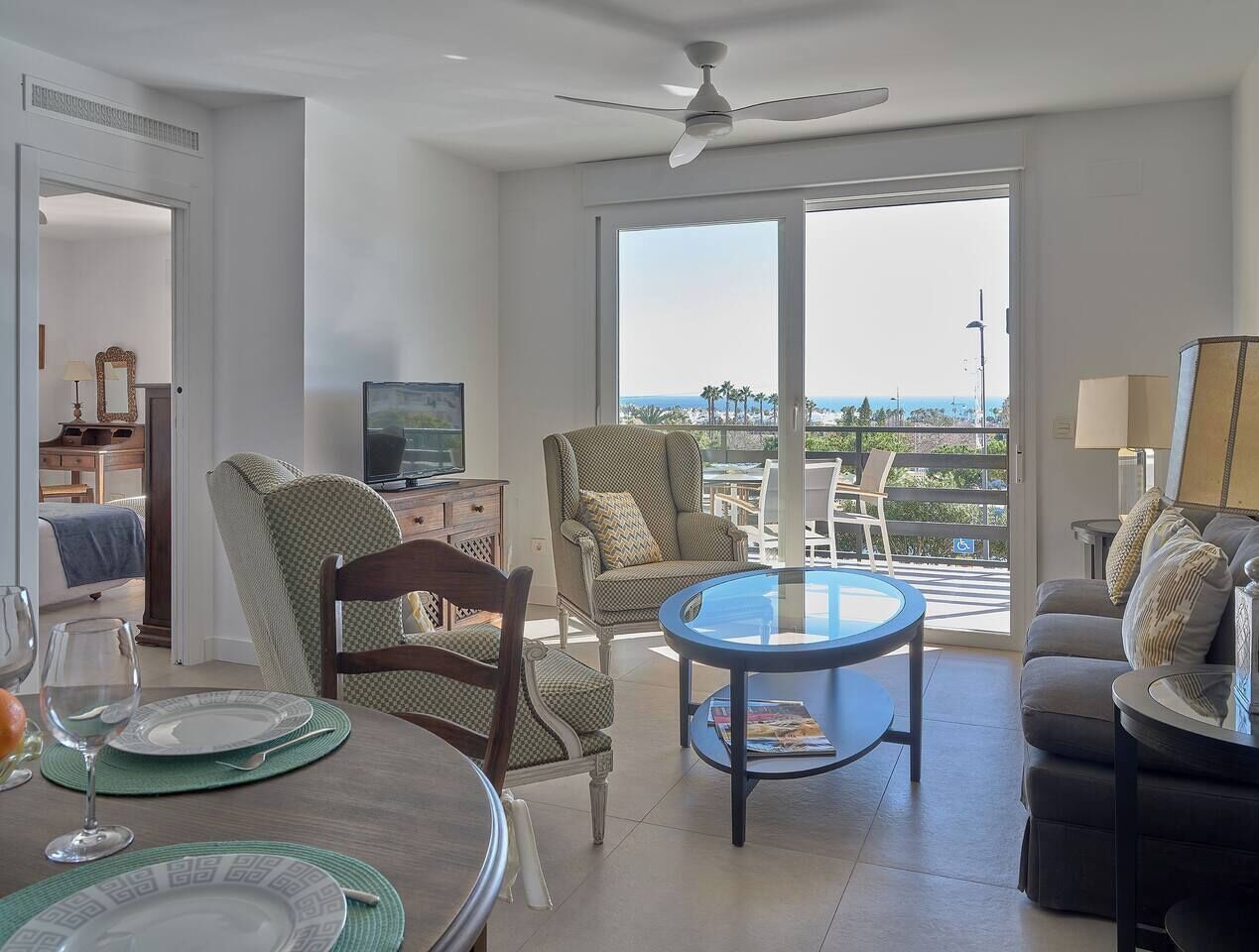 A spacious living area with a balcony, a dining table, and comfortable seating.