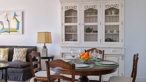 A dining area with a round table, four chairs, a cabinet with glass doors, and a sofa with cushions. - Ocean View Apartments on Boulevard, Apartame. (San Pedro Alcántara)