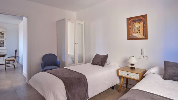 A bedroom with two beds, a chair, a wardrobe, a bedside table with a lamp, and a painting on the wall. - Ocean View Apartments on Boulevard, Apartame. (San Pedro Alcántara)