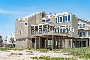 Ein mehrstöckiges Strandhaus mit Balkon und überdachter Veranda.