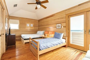 A wooden-paneled room with two beds, a ceiling fan, and a large window. - Steps from the Beach, Pet Friendly, Warm Interior with Great Views (Galveston)