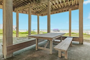 En paviljong vid stranden, byggd av trä, med bänkar och ett picknickbord.