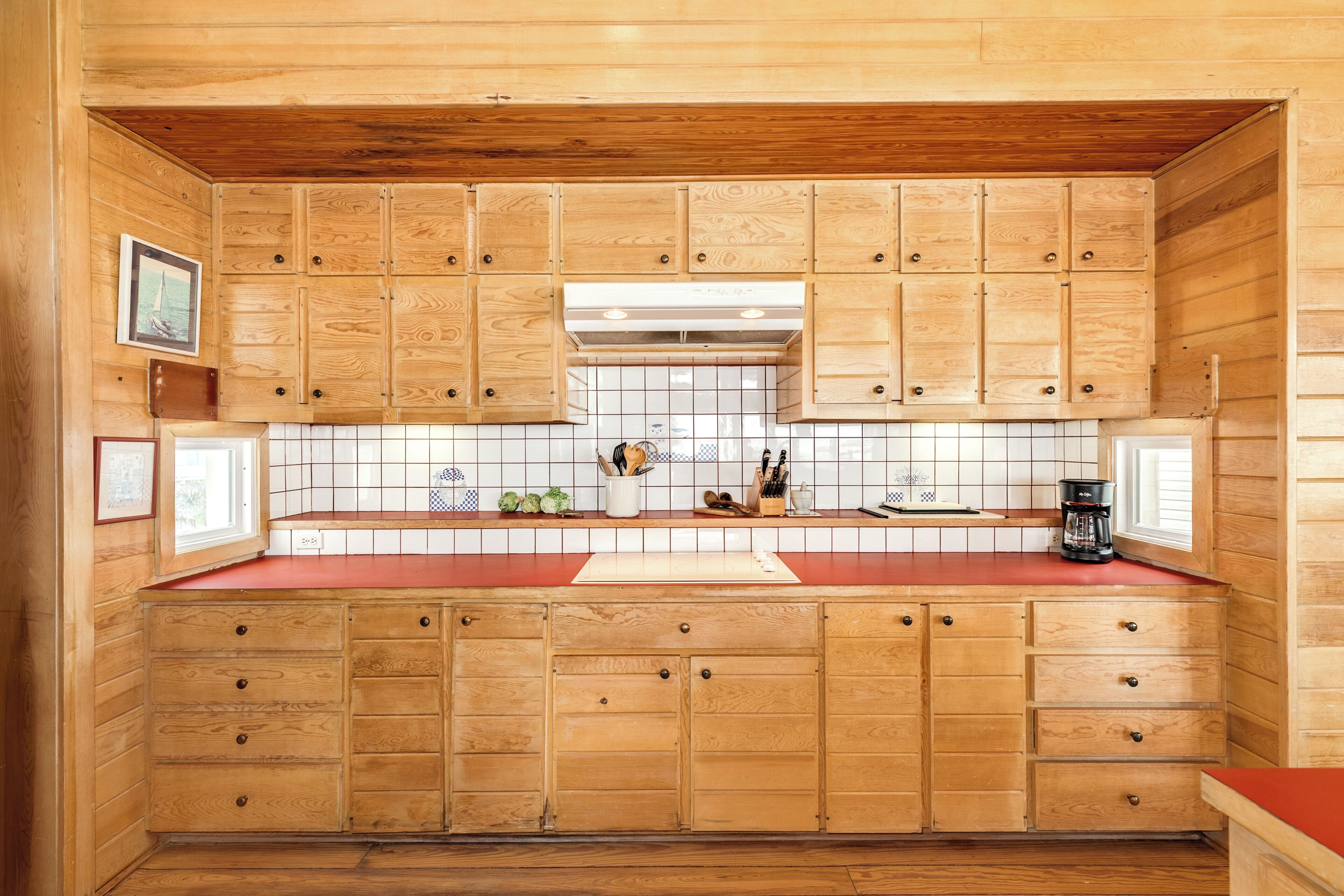 Una cocina con armarios de madera, una encimera roja y un salpicadero de azulejos.