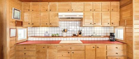 Una cocina con armarios de madera, una encimera roja y un salpicadero de azulejos.