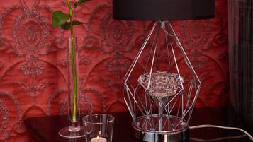 A table with a black lamp, a crystal vase, a lit candle, and a white rose.