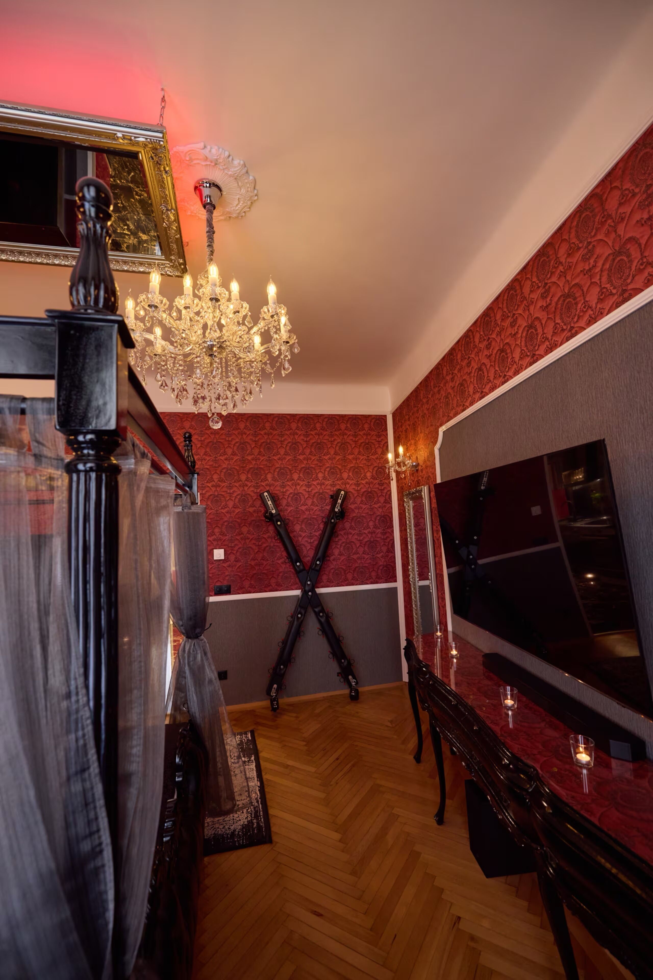 Una habitación con una araña, un espejo y una pared con estampado rojo.