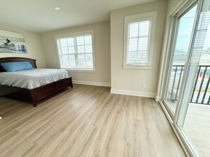 Een slaapkamer met een bed, twee ramen en uitzicht op buiten.