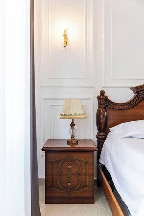 Un dormitorio con una cama de madera, una mesita de noche con lámpara y un aplique en la pared.