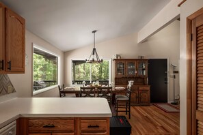 Une cuisine dotée d’un grand îlot central, de meubles en bois et d’un coin repas avec des chaises et une table.