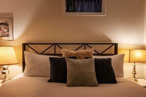 A neatly made bed with a headboard, multiple pillows, and two bedside lamps. - Mountain Cabin with Arcade, Hot Tub & Fire Pit (Berkeley Springs)