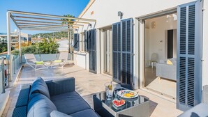 A modern outdoor patio with a sofa, chairs, a table with drinks, and a pergola. - Beachfront Villa With Pool, Puerto Pollenca (Pollença)