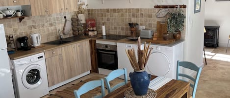 Una cocina moderna con armarios de madera, horno empotrado y comedor con mesa y sillas de madera.