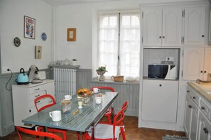 Eine Küche mit Esstisch, Stühlen, Wasserkocher, Mikrowelle und Schränken.