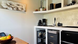 A modern kitchen with a coffee maker, a refrigerator, and a fruit bowl on the counter. - Bevimar Moonlight Suite with Private Pool and Non Heated Jacuzzi (Finikia)