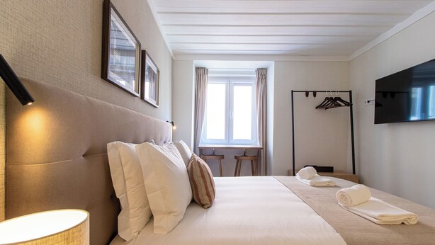 Ein Hotelzimmer mit Bett, Schreibtisch, Fernseher und Kleiderhaken.