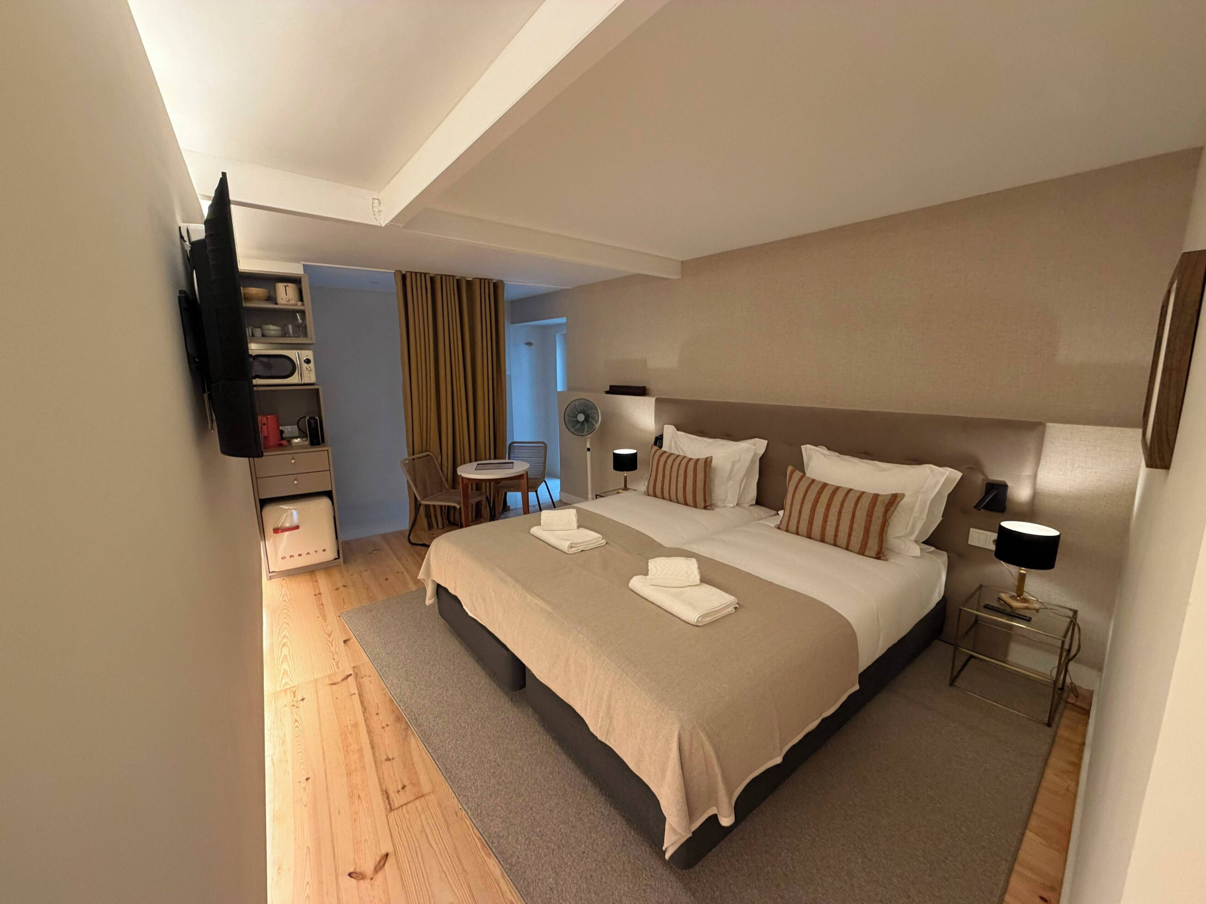Une chambre d’hôtel avec un grand lit, des tables de chevet, un téléviseur à écran plat, un bureau et une chaise.