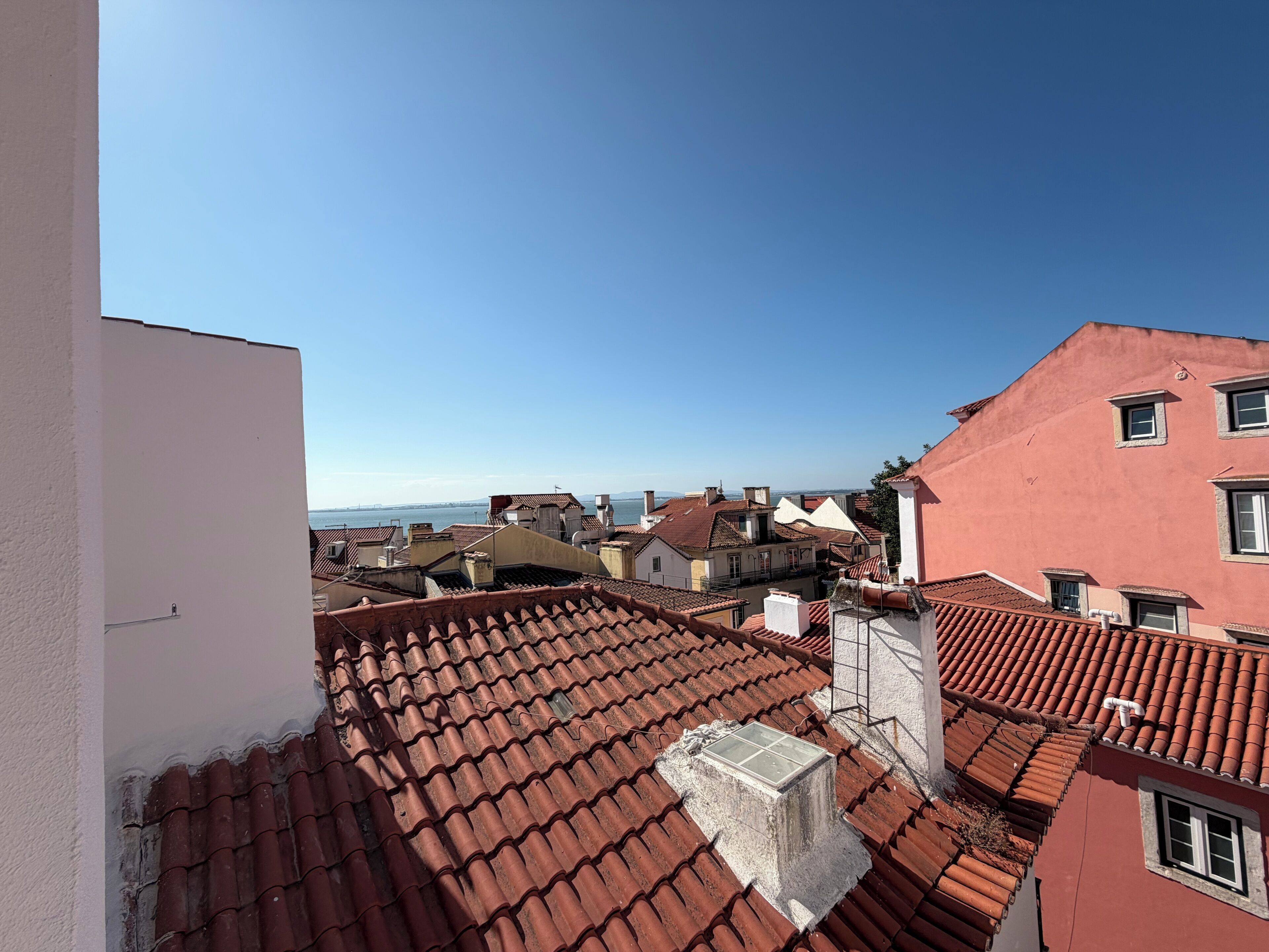 A view of terracotta-tiled rooftops with buildings in the background.
