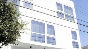 Un edificio moderno con fachada blanca, ventanas grandes y escaparate donde se lee 'ROMA'.