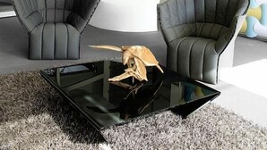 Una sala de estar moderna con dos sillones de cuero, una mesa de centro de vidrio y un mostrador de recepción blanco.