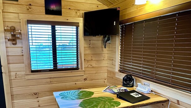 Een houten interieur met een tafel, een bank en luiken.