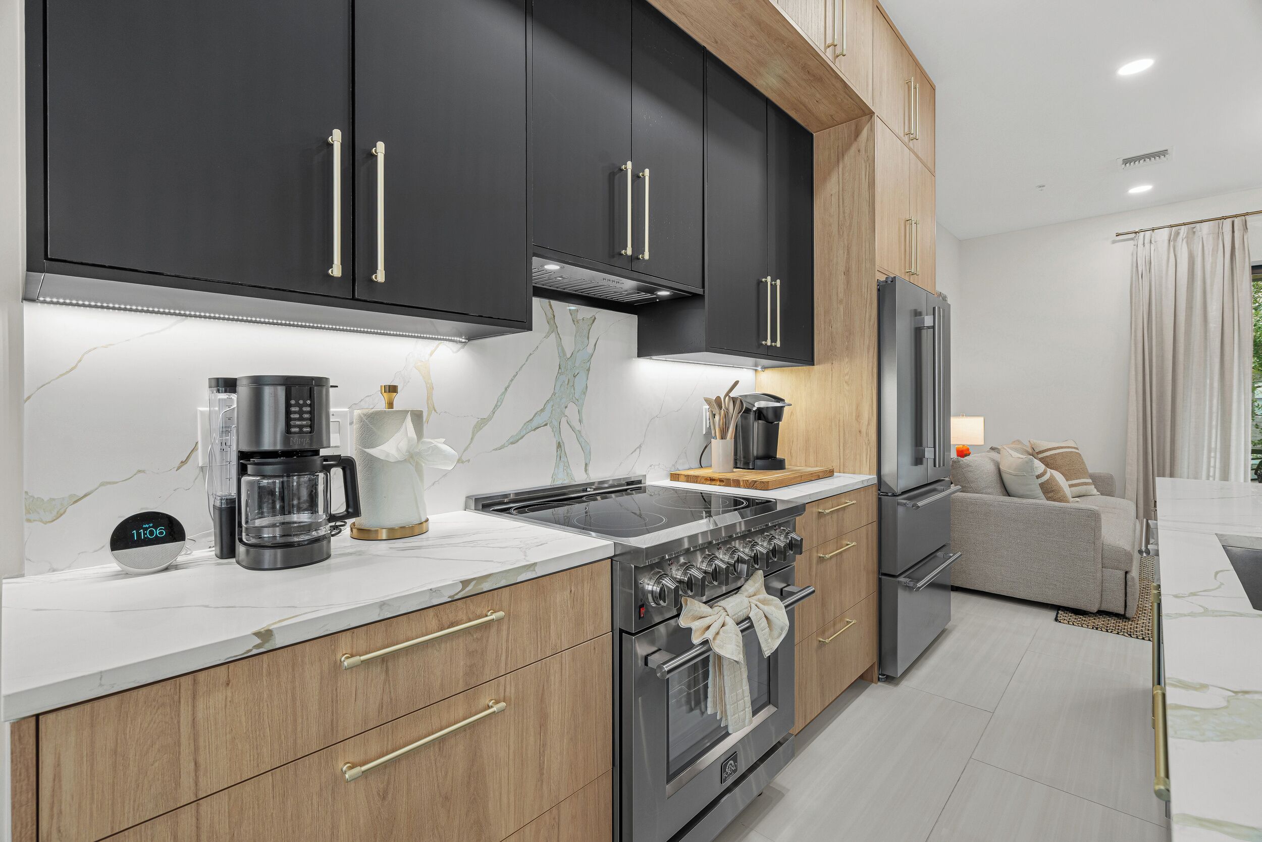 A modern kitchen with dark cabinets, a coffee maker, a stove, and a refrigerator.