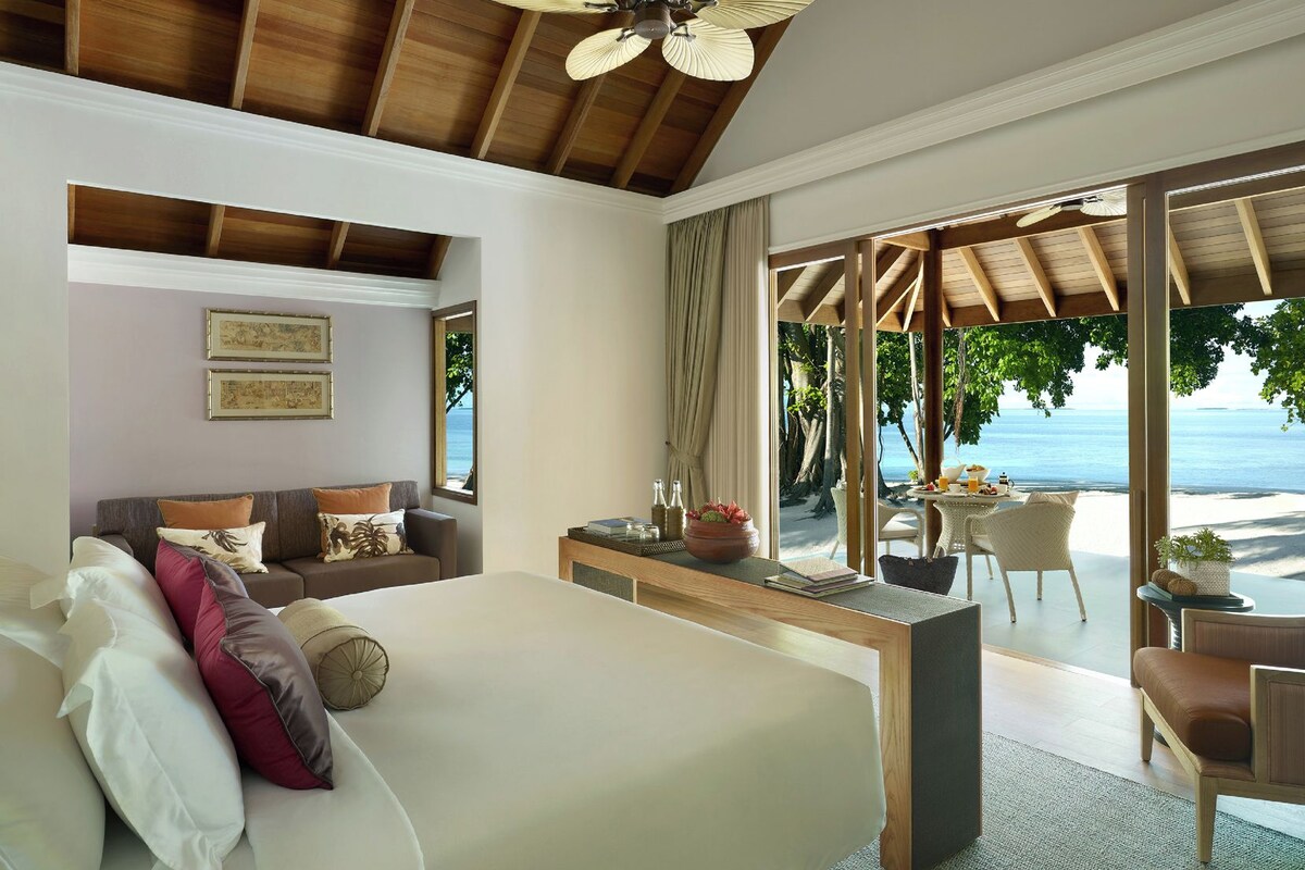 A bedroom with a large bed, a desk, and a view of the beach.