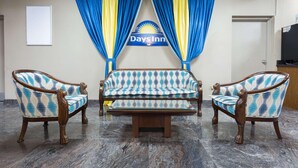 A reception area with a sofa and two armchairs, a sign for Days Inn, and a whiteboard on the wall. - Days Inn by Wyndham Orangeburg (Orangeburg)