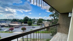 A balcony with a view of a parking lot and buildings. - Stylish 2 Bedroom Apartment Downtown High Point (High Point)