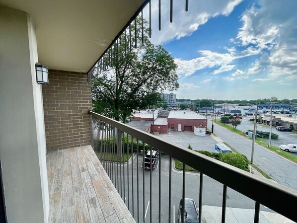 A balcony with a view of a parking lot and buildings.