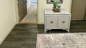 A hallway with a white console table, a mirror, and a door leading to another room. - Stylish 2 Bedroom Apartment Downtown High Point (High Point)