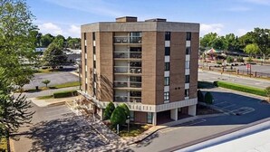 A multi-story building with a flat roof, large windows, and a parking lot in front. - Stylish 2 Bedroom Apartment Downtown High Point (High Point)
