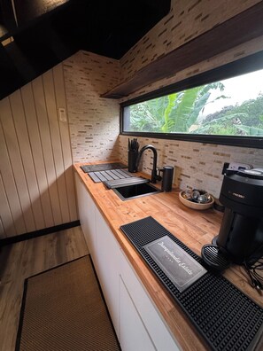 A modern kitchen with a wooden countertop, a black espresso machine, and a window with a view of greenery. - Tranquilandia Estate-Private Villas Retreat (Río Grande)