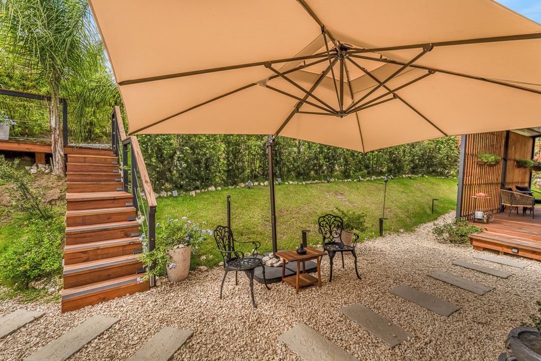 A patio area with a wooden staircase, outdoor furniture, and a large umbrella.